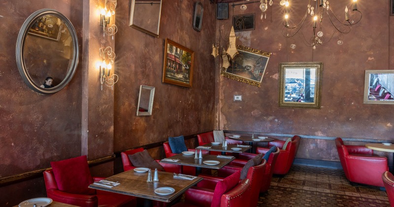 Interior, seating area, tables for two, vintage paintings and mirrors hanged on the walls