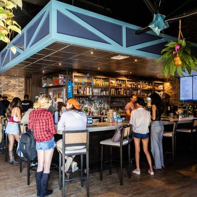 Bar area with people seating on stools and standing at the counter.