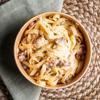 Tagliatelle pasta mixed with a rich sauce, meat pieces and grated cheese.