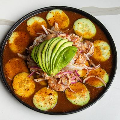 Aguachile garnished with sliced cucumbers, red onions, and avocado.