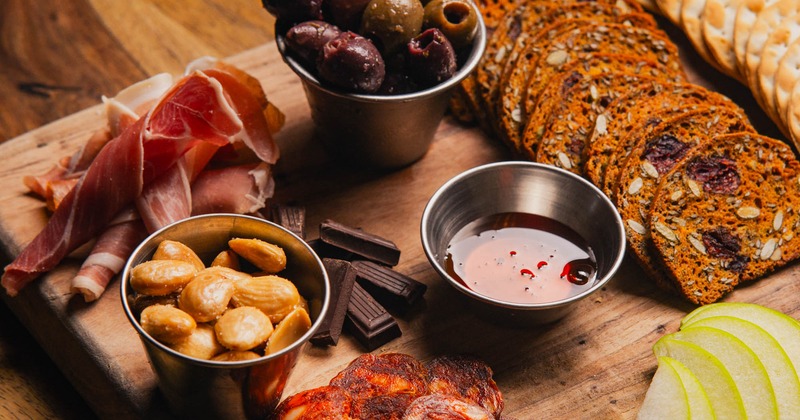 Charcuterie board with meats, crackers, nuts, olives, and fruit
