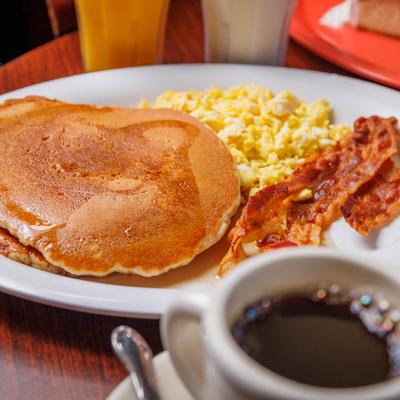Two buttermilk pancakes, two scrambled eggs and two bacon slices