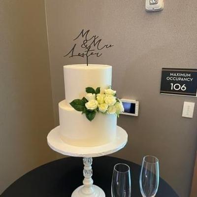 White two tiered cake decorated with white roses