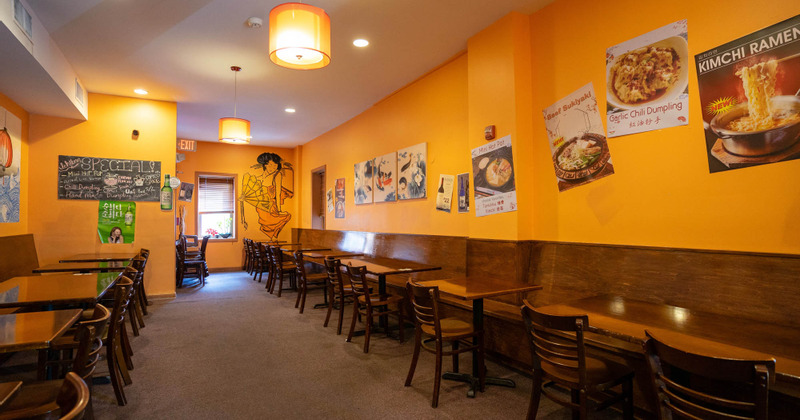 Interior - tables neatly lined by the wall, walls decorated with posters and drawings