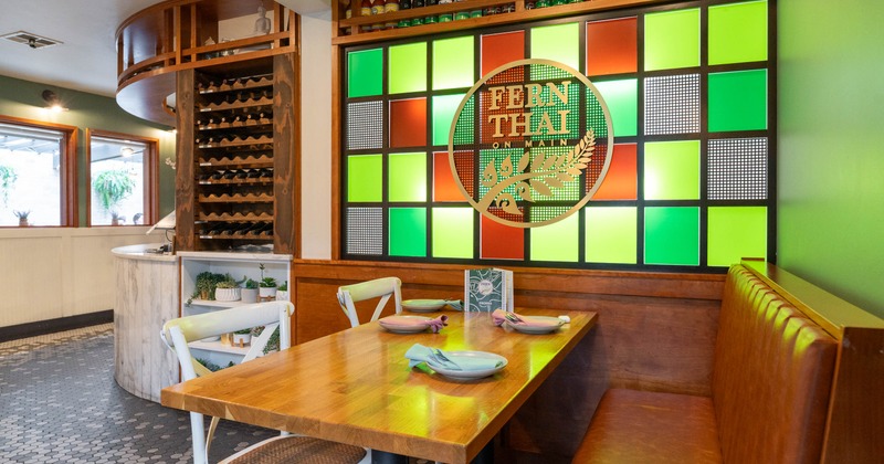 Restaurant interior with a wooden table, colorful wall panels, and a circular logo