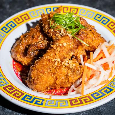 Crispy fried chicken wings served with a side of pickled vegetables.
