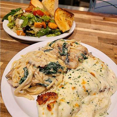 Roman Chicken Alfredo accompanied by pasta primavera, a house salad and garlic bread..
