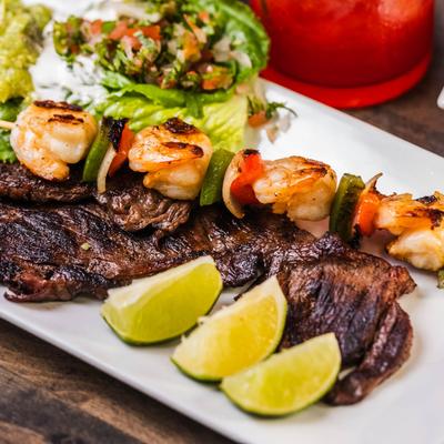 Steak and shrimp veggie skewer served with salad and lime wedges.