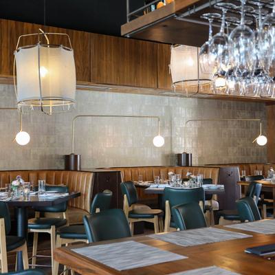 Part of dining room with round booths, tables set with tableware.