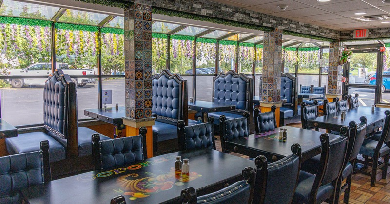 Restaurant dining room with blue tufted booths, colorful tile columns, large windows