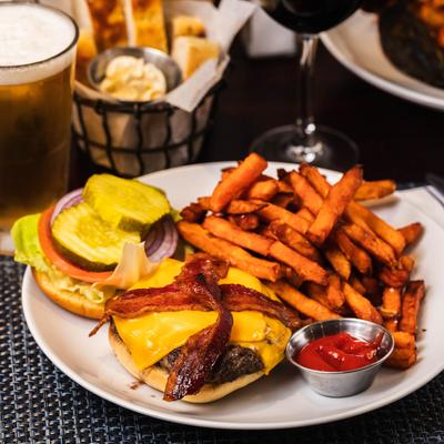 Bacon cheeseburger with a side of fries and ketchup, food and drinks display.
