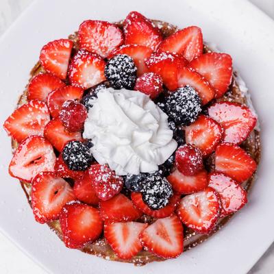 Top-down view of berry waffles with whipped cream.