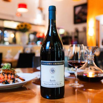 Wine bottle beside a glass of red wine on a restaurant table.