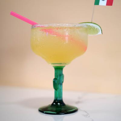 Margarita in salt-rimmed glass, garnished with a lime wedge and small Mexican flag.