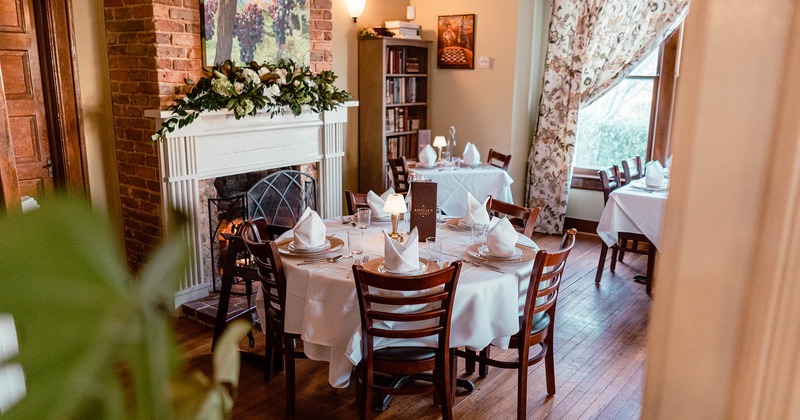 Table for four ready for guests, decorated fireplace in the back