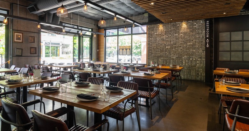 Interior, dining area, tables for four, gray brick wall, large folding doors, concrete flooring