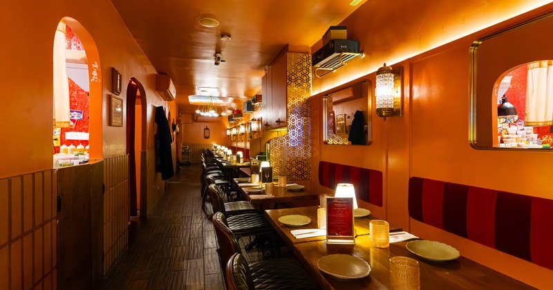 Cozy, warm and intimate restaurant interior with set tables lining one side of the room