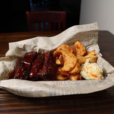 Barbecue ribs with potato wedges and coleslaw.