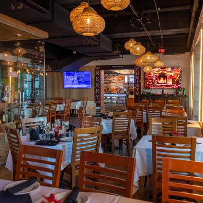 Dining room with set tables, wooden chairs, and rattan pendant lights.