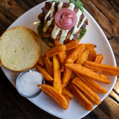 Blackened Fish sandwich with sweet potato fries and a sauce on the side.