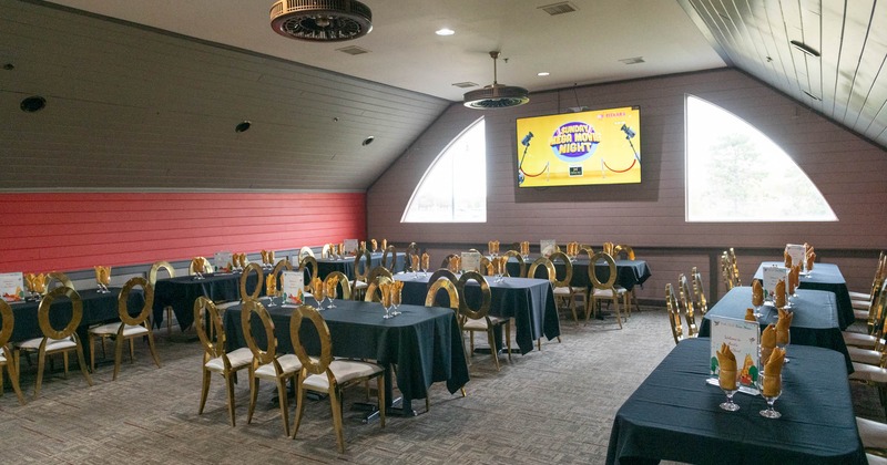 Interior, seating area, tables for six, carpet flooring, large TV, triangular windows