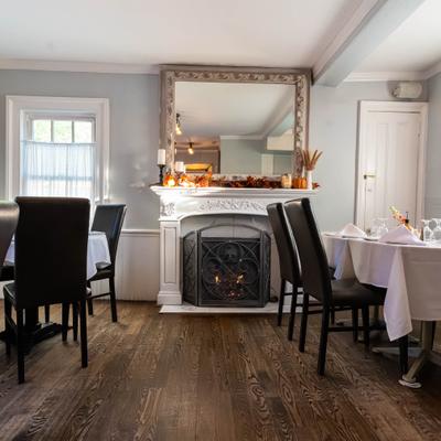 Dining room featuring dark wooden flooring, black dining chairs and a fireplace.