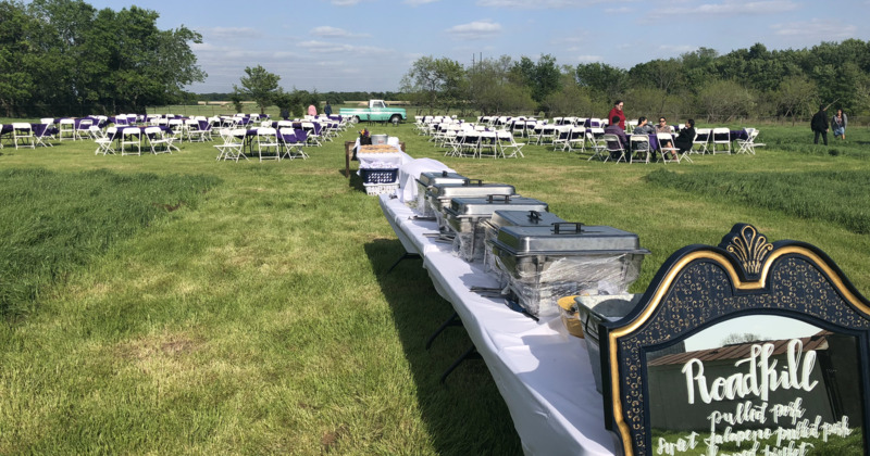 Lawn space with tables for guests and catering tables with steel chafer dishes