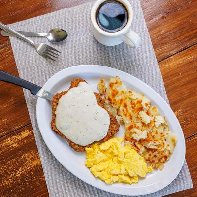 Country fried steak with scrambled eggs, hash browns. and coffee.