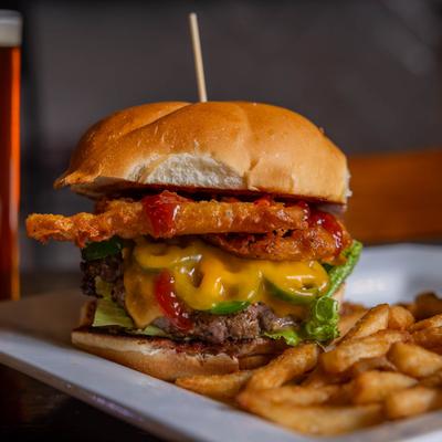 Cowboy burger with cheddar cheese, lettuce, and onion rings, served with fries.