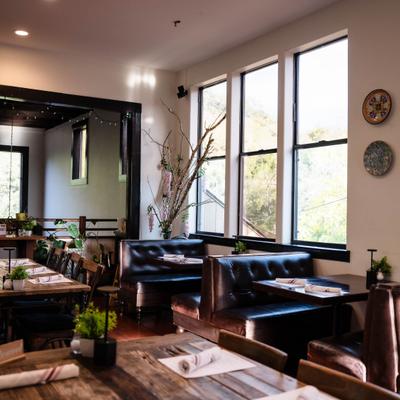 Dining room with both booth and table seating, plants and decorations.