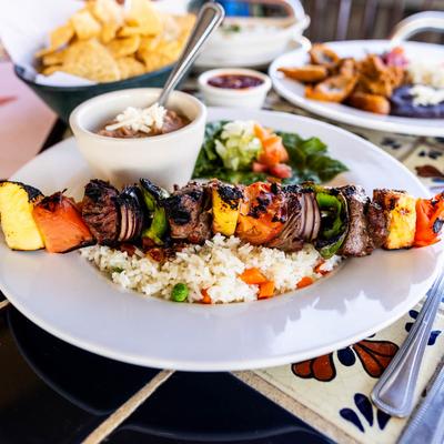 Grilled beef tenderloin skewer with vegetables, served with rice with beans.