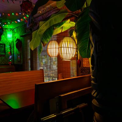Interior of dining area, close up of wooden booths, soft lantern light, palm plant.
