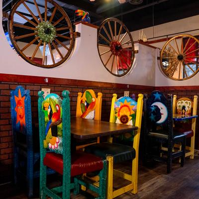 Interior with colorful wooden chairs and decorative wagon wheels on the wall.