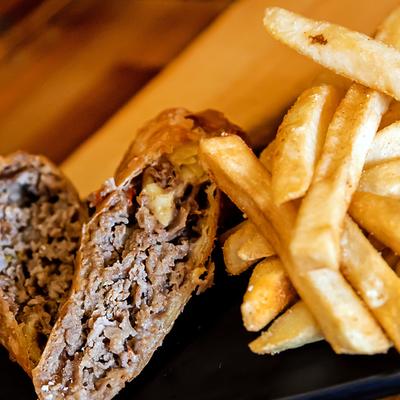 Steak eggrolls with onions, pepper, and cheese served with fries.
