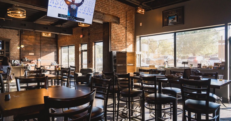 Interior with exposed brick walls, wooden tables and large windows.