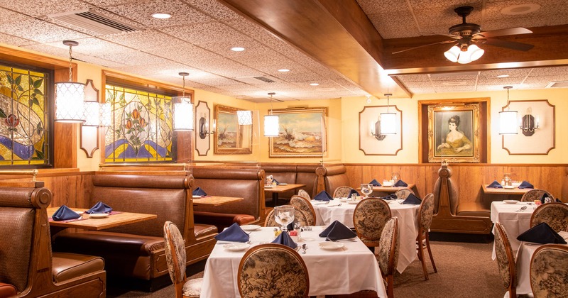 Interior, set dining tables and booths, walls decorated with framed painitngs