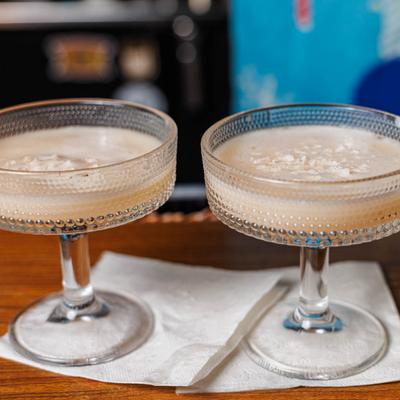 Two creamy beige cocktails in elegant coupe glasses.