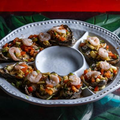 Mexican-style prepared oysters topped with a savory mix of diced vegetables and shrimp.