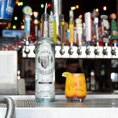 Cocktail on a lowball glass sevred alongside a bottle of tequila.