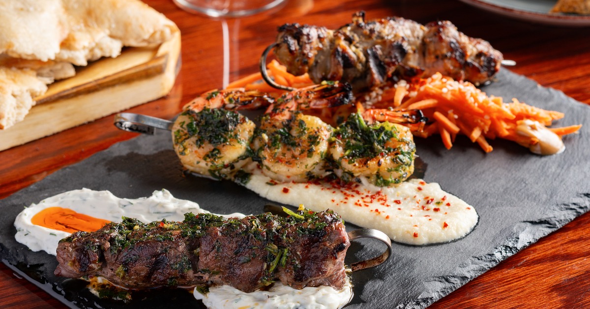 Mediterranean-style grilled shrimp and meat skewers served on a dark slate platter