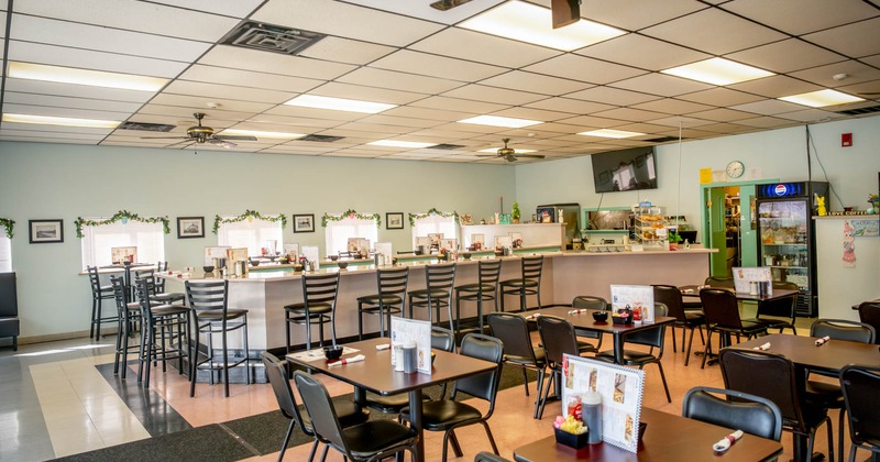 Interior, dining area, tables with chairs, ready for guests, bar with stools in the back