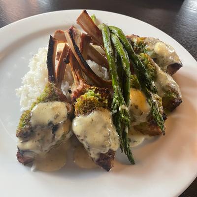 Lamb chops, smothered in sauce, on a bed of rice, with grilled asparagus