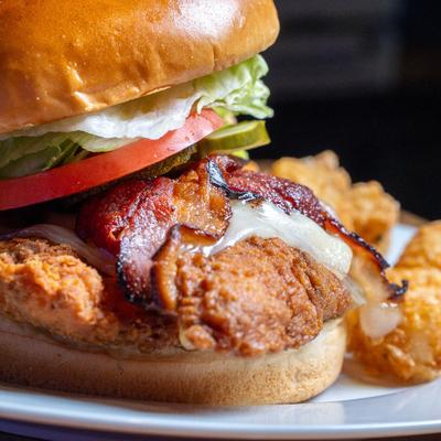 Chicken breast and Swiss sandwich, served with tots, close up.