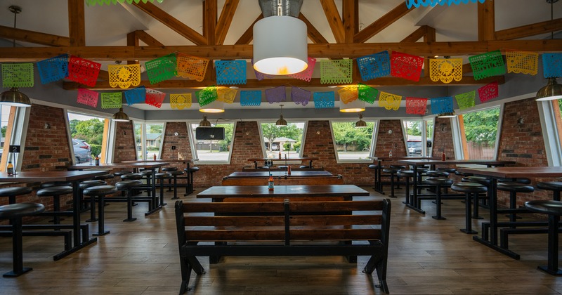 Seating area with benches and tables in the center and high tables and round stools along the sides