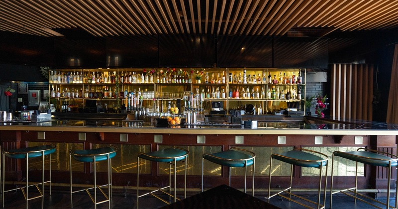 Interior, bar area, marble top bar with stylish bar stools, large brass drink shelf