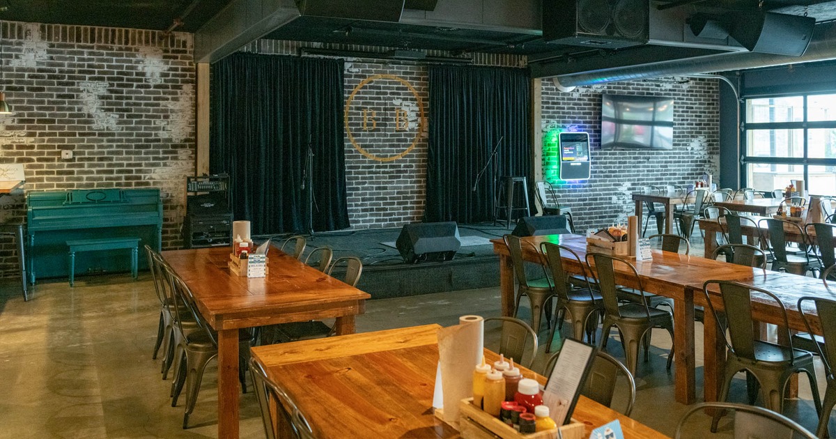 Interior, open space dining area, band stage, small piano in the corner, brick walls