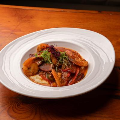 Shrimp and grits with sausage slices, peppers and microgreens.