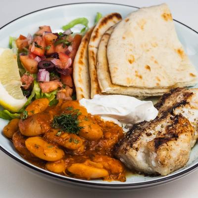 Fish filet served with giant beans, pita bread, salad, lemon wedge, tzatziki.