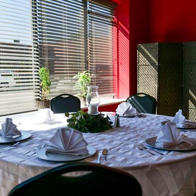 Table set with plates, napkins and cutlery, next to a window.