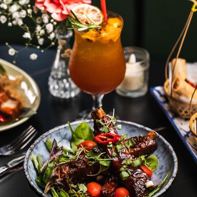 Seasoned charred marinated pork spare ribs with barbecue sauce, served with a cocktail.